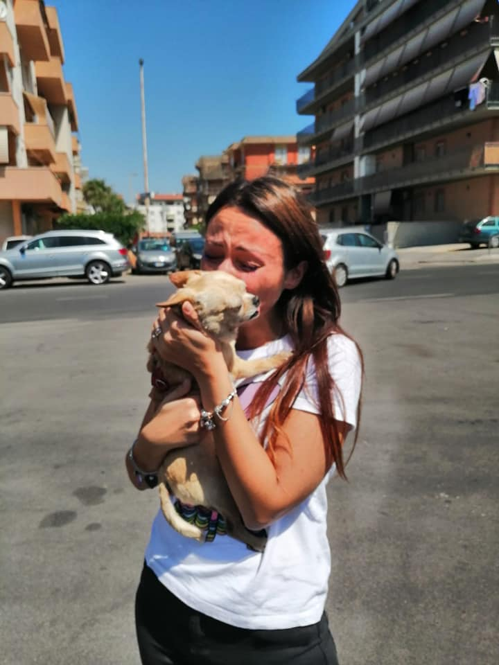 A woman is hugging a dog on the street.